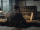 Alan Turing devant une machine de décryptage dans un bureau des années 1940